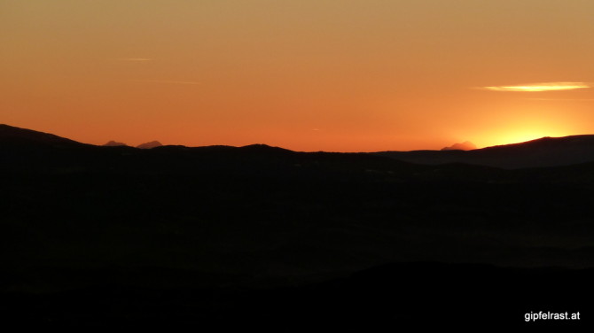 Seltene Gipfel: Die Sonne versinkt neben dem slowenisch-kärntner Dreigestirn aus Vertatscha, Hochstuhl und Triglav.